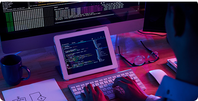 Developer workspace with code on laptops in neon lighting